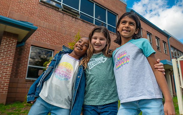 Three girls with their arms around each other's shoulders